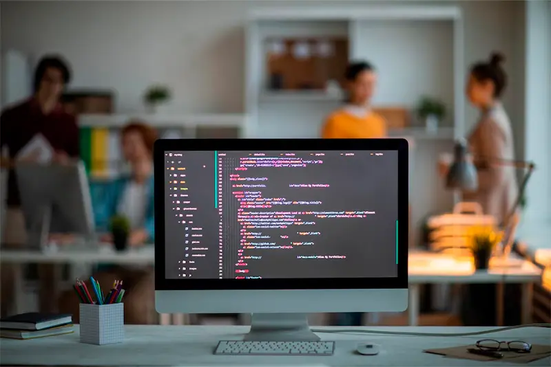 Imagem de tela com código de programação com equipe ao fundo